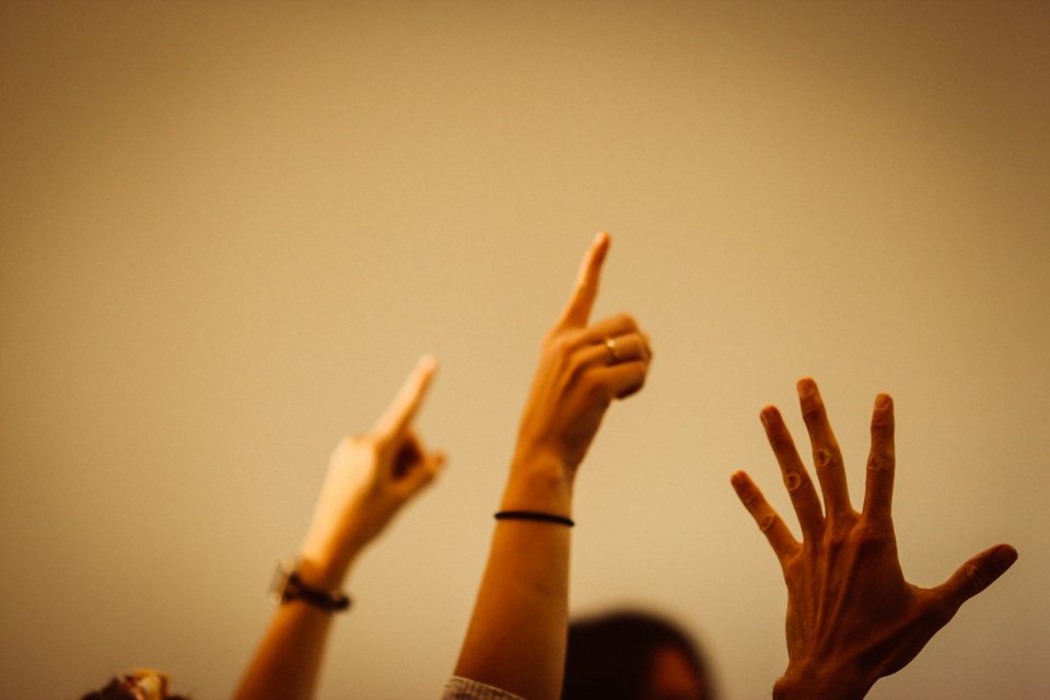 person in black long sleeve shirt raising right hand